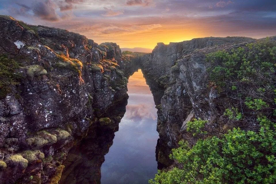 Ein schmaler Spalt zwischen moosbedeckten Lavawänden bei Þingvellir bei Sonnenuntergang