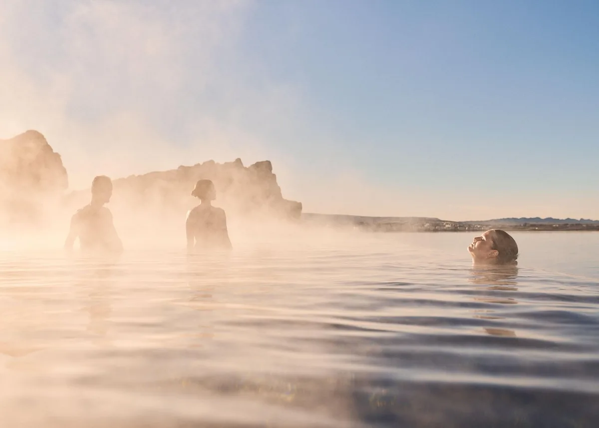 Bathers standing in soft mist in the warm lagoon at golden hour